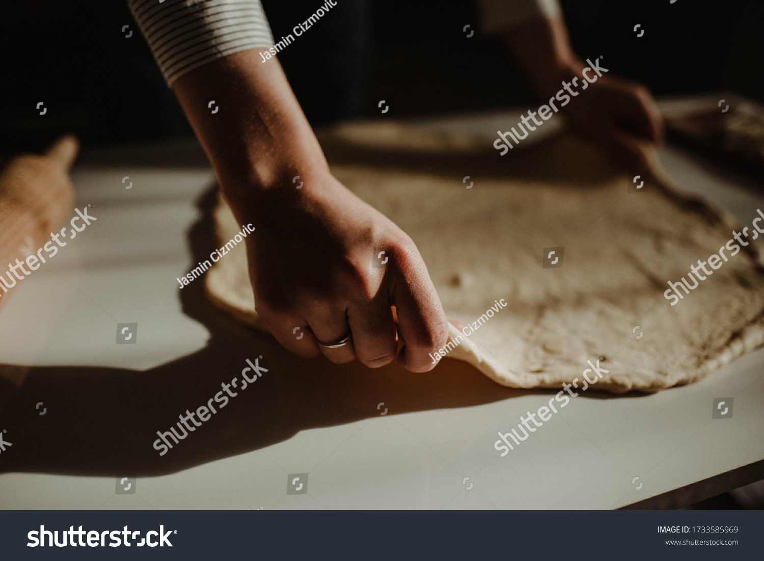 Wife making a homemade doughy pastry food with smoked cheese during Ramadan for dinner during the sunset light in the home on the wooden table #1733585969