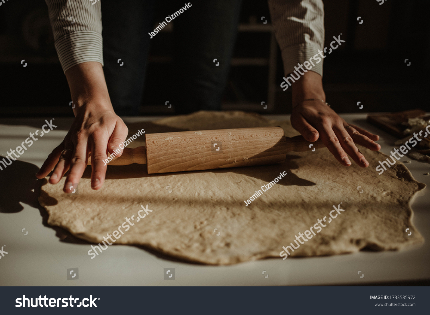 Wife making a homemade doughy pastry food with smoked cheese during Ramadan for dinner during the sunset light in the home on the wooden table #1733585972