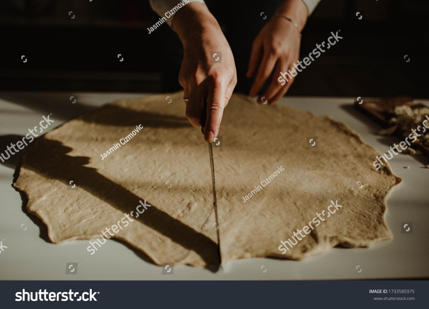 Wife making a homemade doughy pastry food with smoked cheese during Ramadan for dinner during the sunset light in the home on the wooden table #1733585975