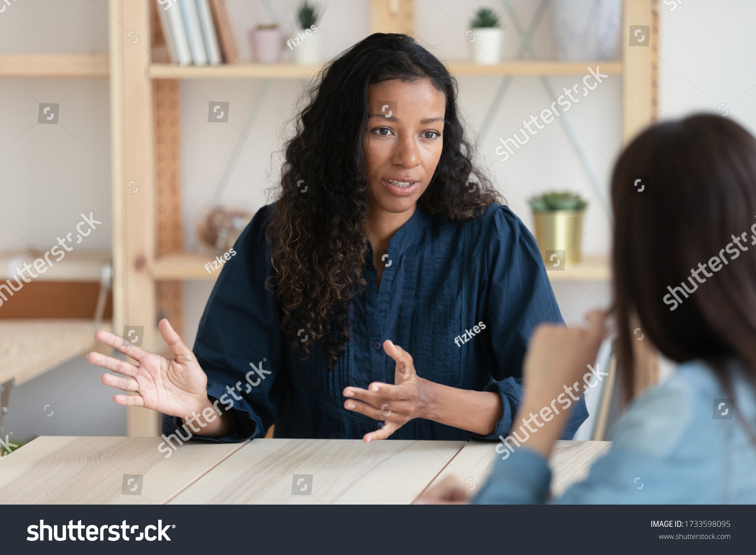 Close up confident african american businesswoman explaining new responsibilities to female applicant. Attractive young diverse woman hr manager talking and introduction company to job seeker. #1733598095