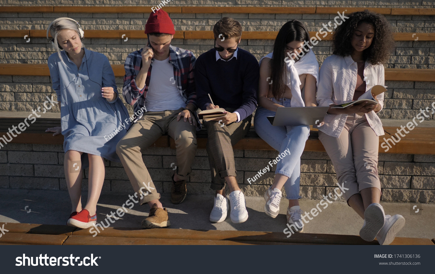 Five friends sitting together, each is busy with another activit #1741306136