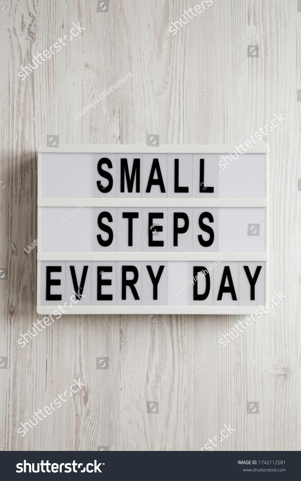 'Small steps every day' words on a lightbox on a white wooden surface, top view. Overhead, from above, flat lay.  #1742112581