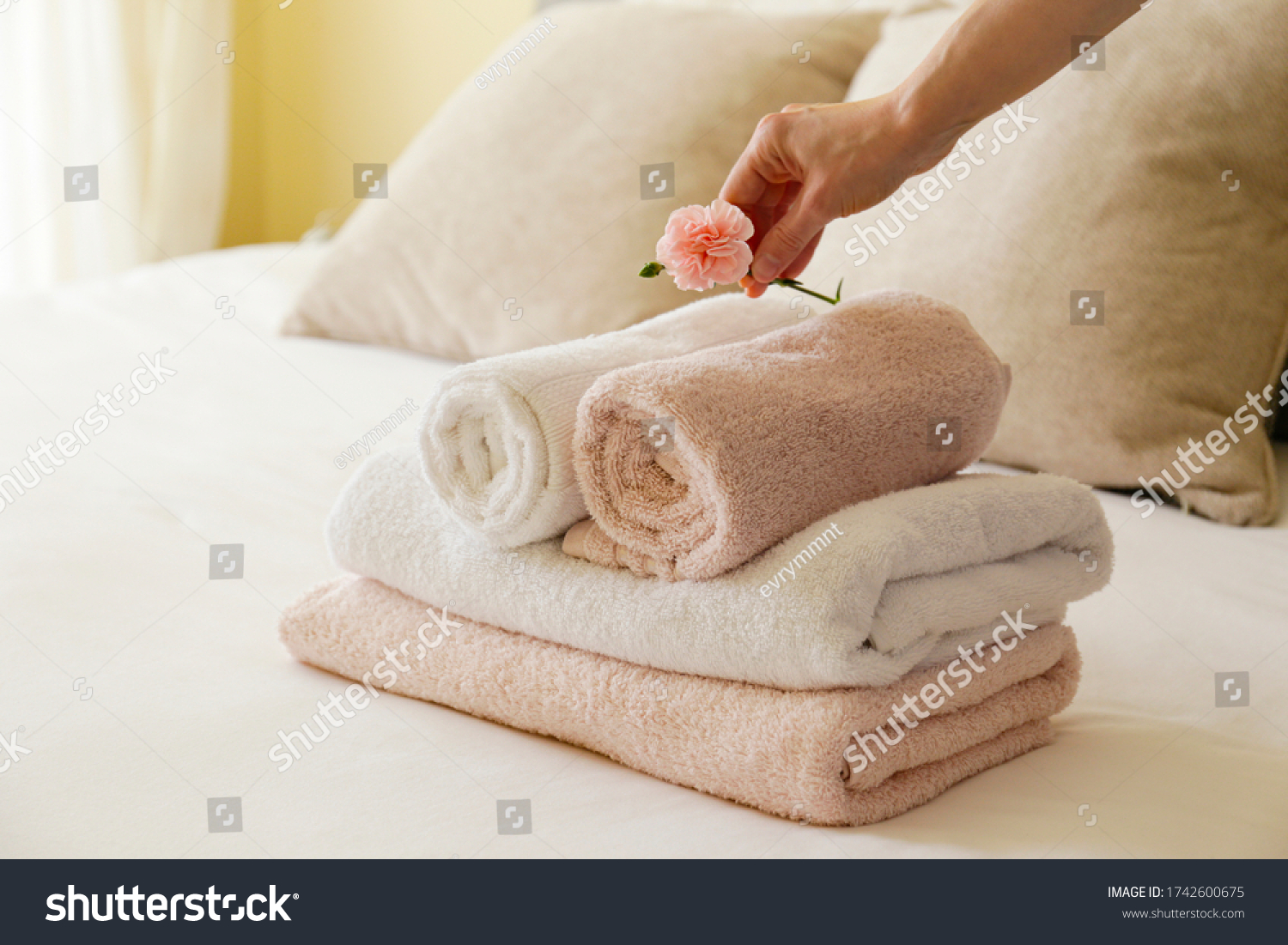 House keeping lady changing the set of folded and stacked towels in hotel room with freshly made bed, perfectly clean and ironed sheets in natural sun light. Close up, copy space for text. #1742600675