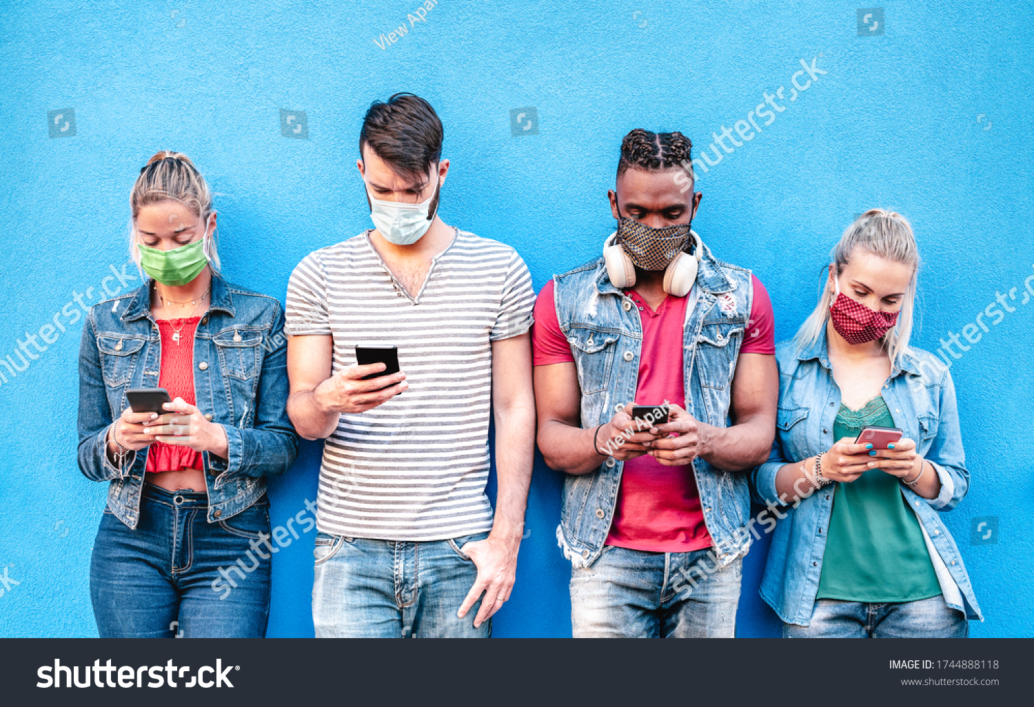 Multiracial friends with face masks using tracking app with mobile smart phones - Young milenial people watching content on social media networks - New normal lifestyle concept - Bright vivid filter #1744888118