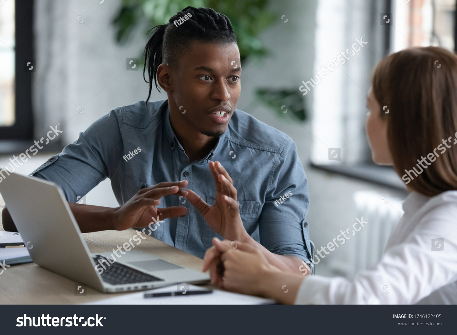 Confident African American team leader mentor teaching new employee, giving instructions to businesswoman, diverse colleagues sharing ideas, working on project together, discussing strategy #1746122405