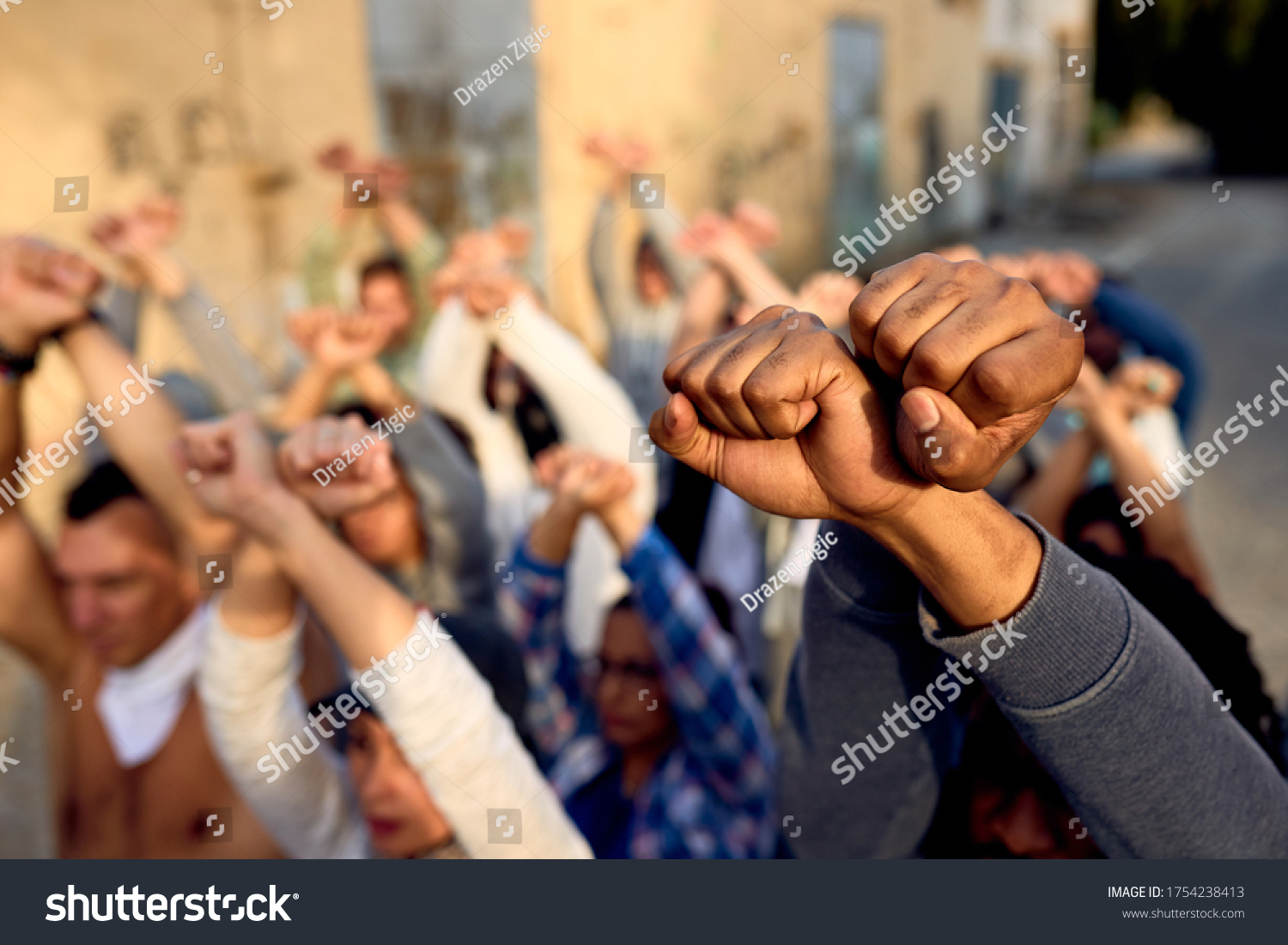 Close-up of large group of protesters with clenched fists above their heads on public demonstrations.  #1754238413