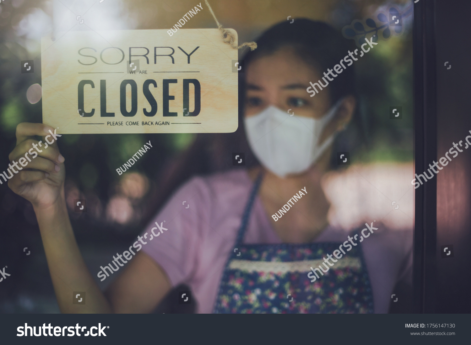 Close up shot of woman wearing mask and hand turning closed sign board on glass door in coffee shop and restaurant after coronavirus lockdown quarantine.Business crisis concept. #1756147130