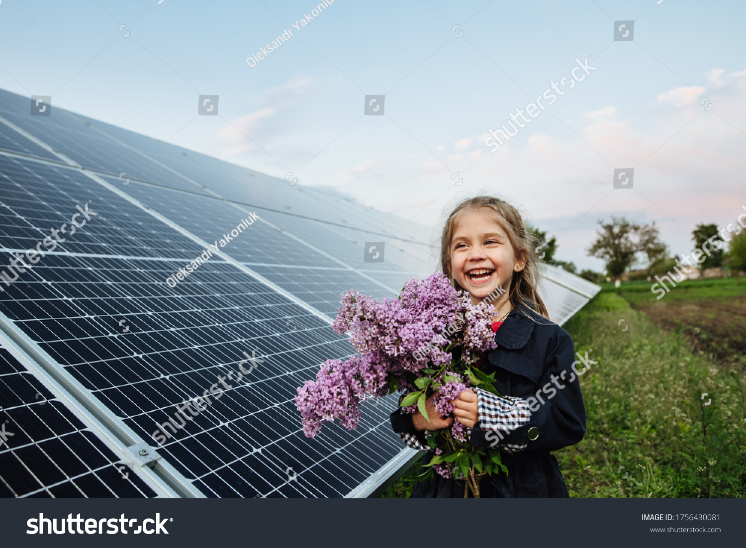 A child with a future of alternative energy and sustainable energy. The child holds flowers on a background of solar panels, photovoltaic. Environmental friendliness and clean energy concept. #1756430081