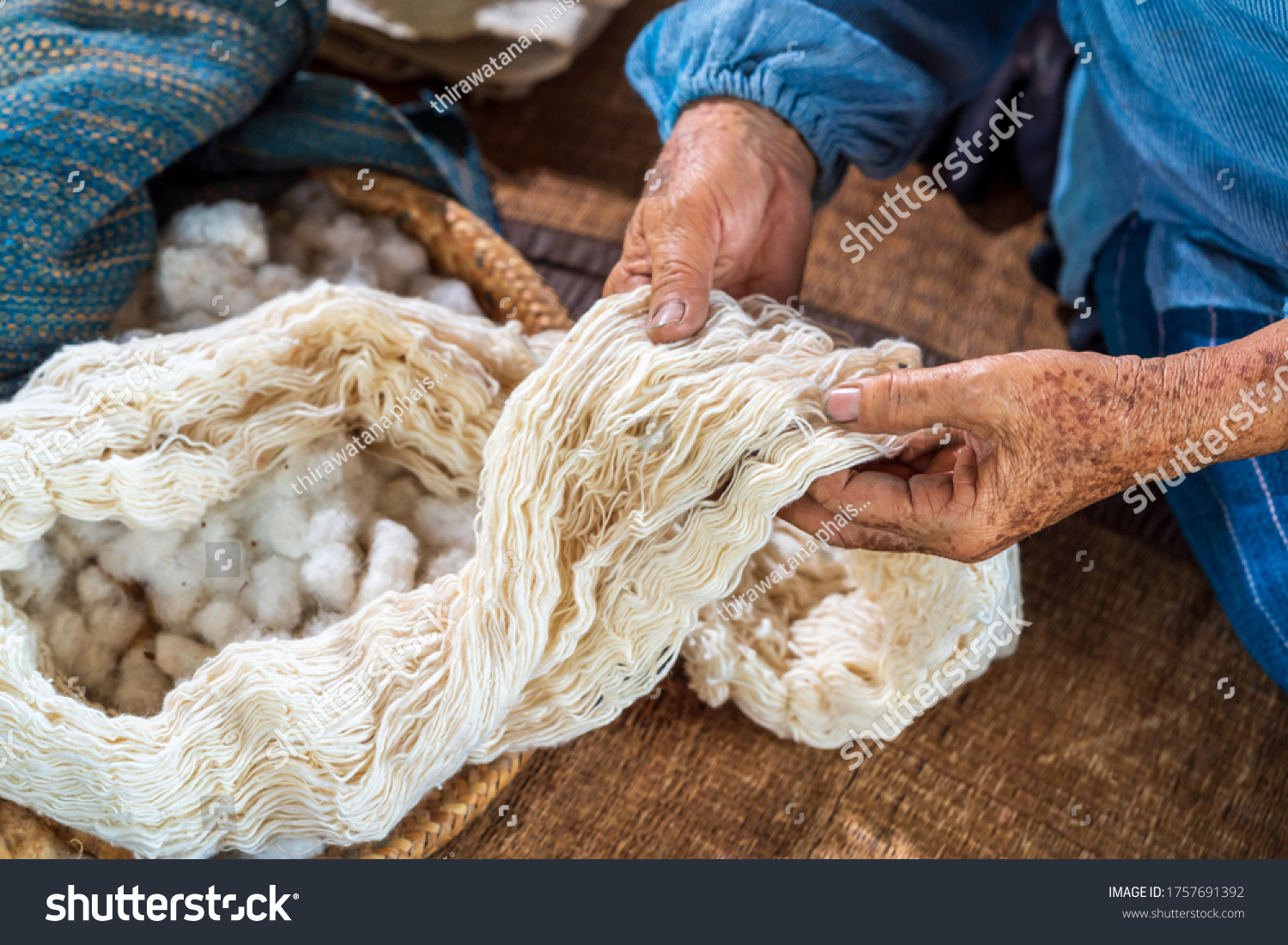 Craftsmen of Thai indigo cotton. An elderly woman is examining the thread made of cotton. Local Master are the original Indigo Cotton Weaving in the community of Sakon Nakhon province. #1757691392
