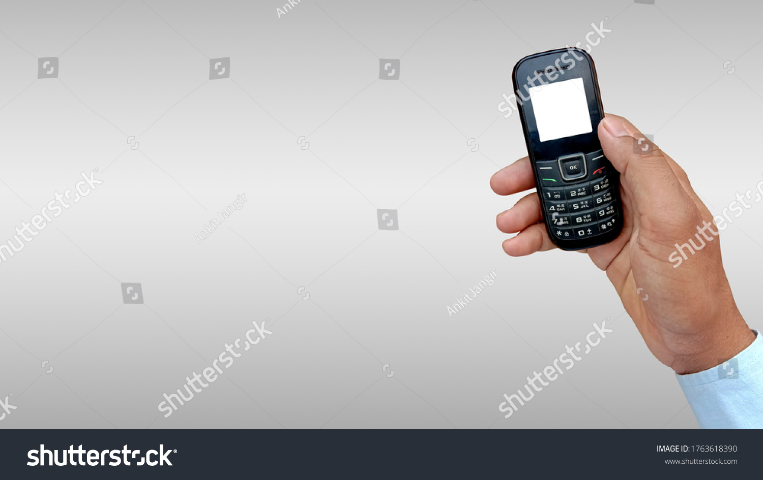 Asian man holding feature or keypad phone in hand #1763618390
