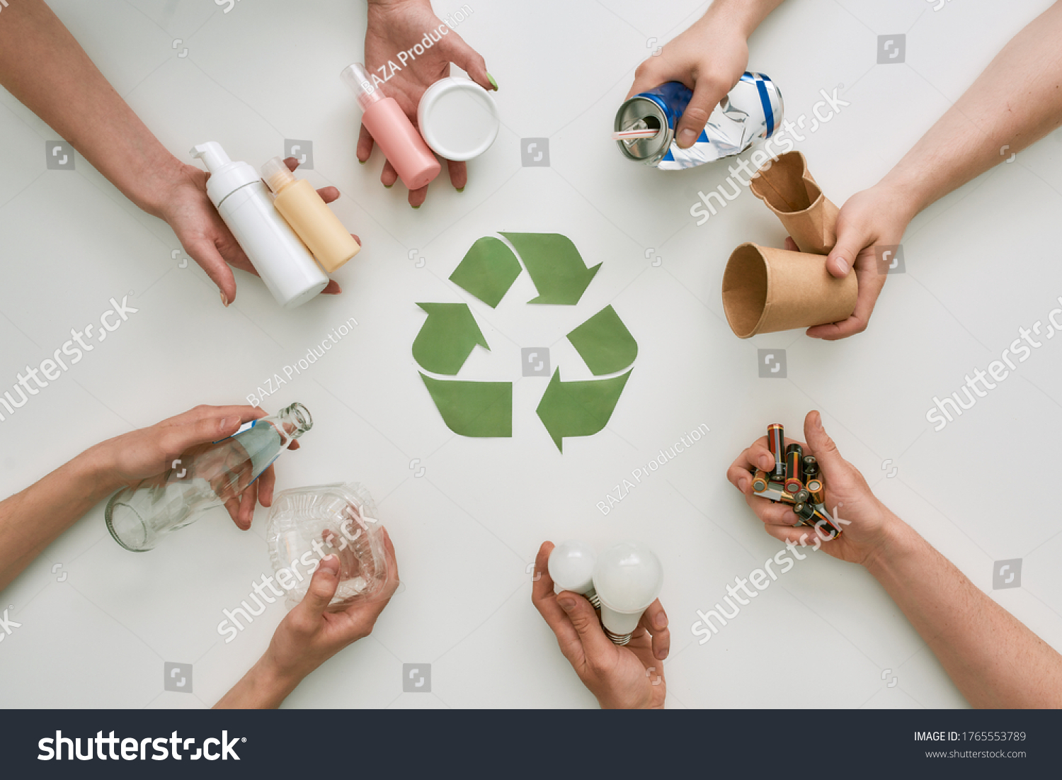 Top view of many hands holding different waste, garbage types with recycling sign made of paper in the center over white background. Sorting, recycling waste concept. Horizontal shot. Top view #1765553789