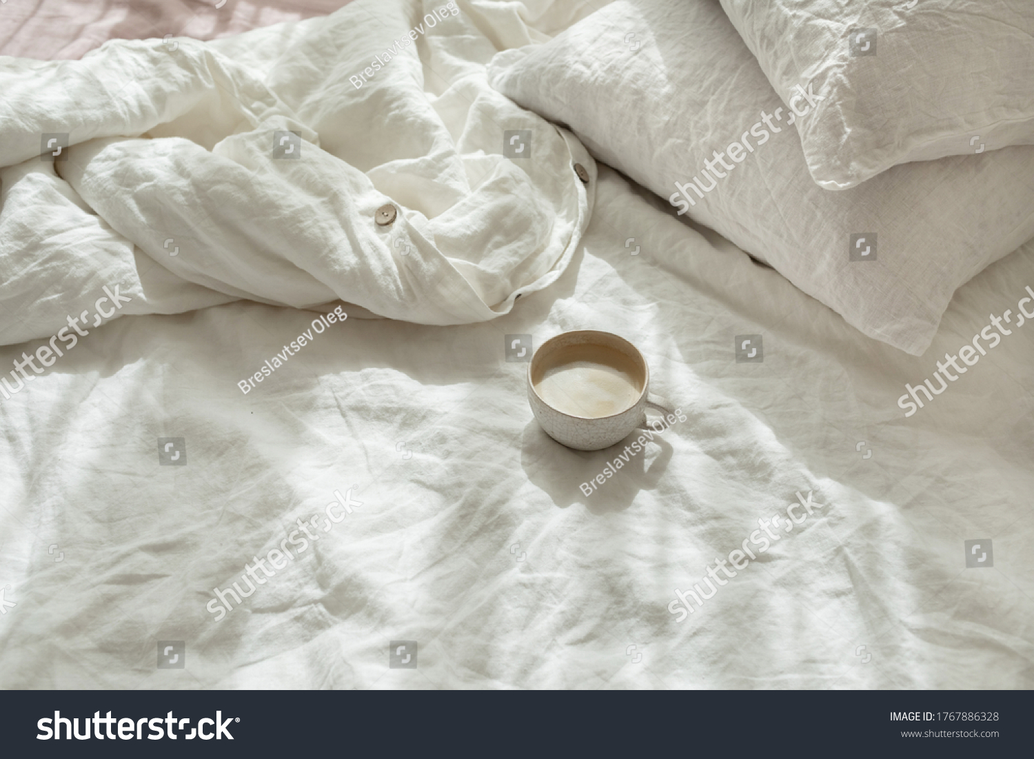 Cup of fresh coffee in bed, morning mood. Linen cotton textile bedclothes. Organic and natural linen. Cozy bedroom interior. Beautiful light. #1767886328