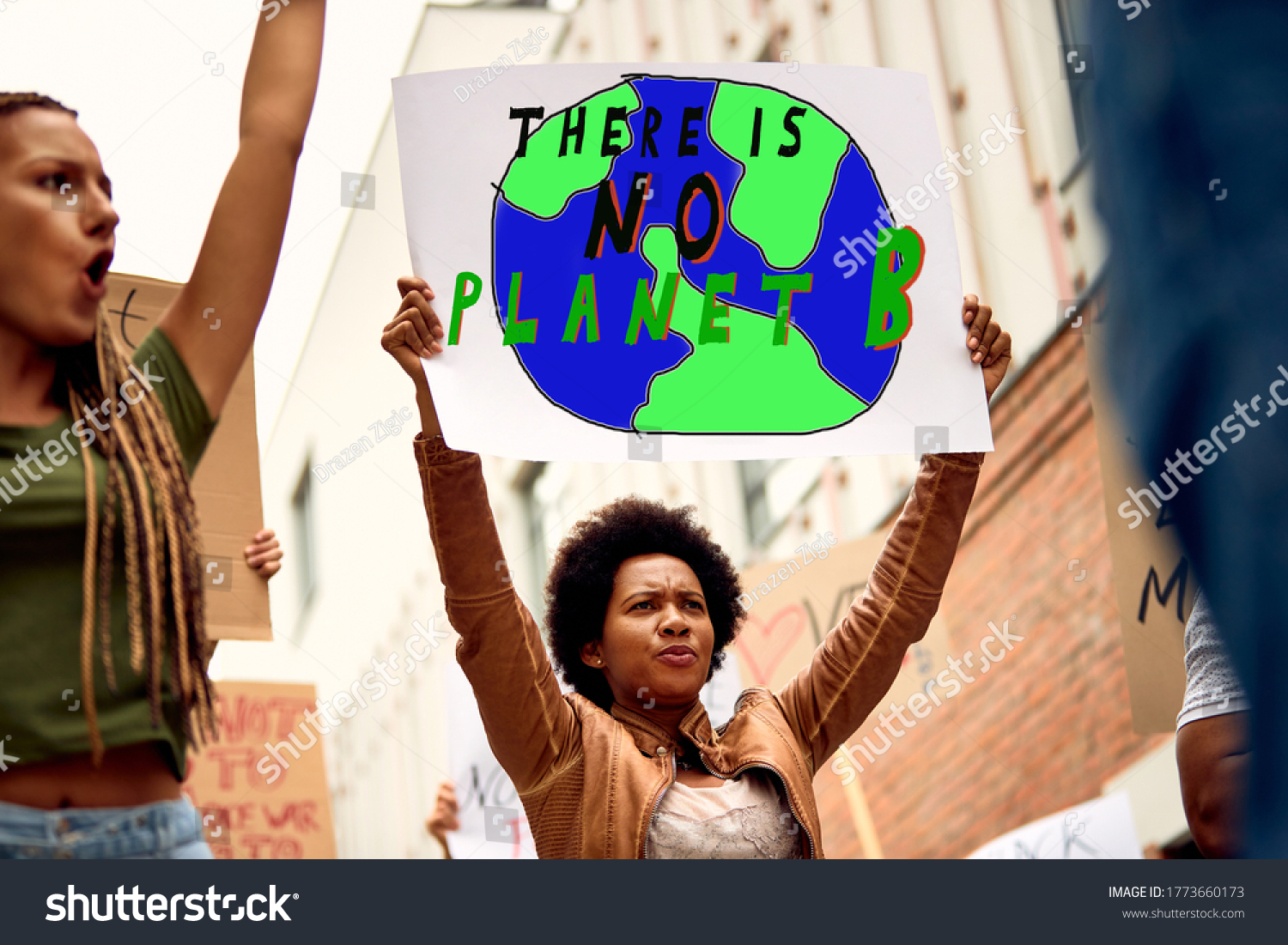 Low angle view of African American woman carrying banner with there is no planet B inscription while protesting with crowd of activists against climate changes. #1773660173