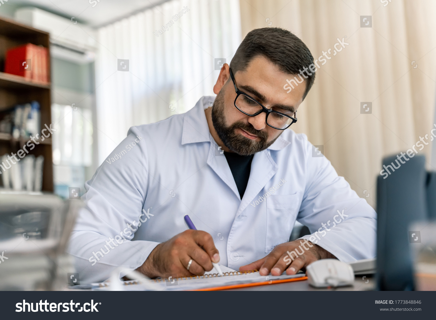Serious doctor sitting at computer. Medical office. Doctor at work. Diagnosing. #1773848846