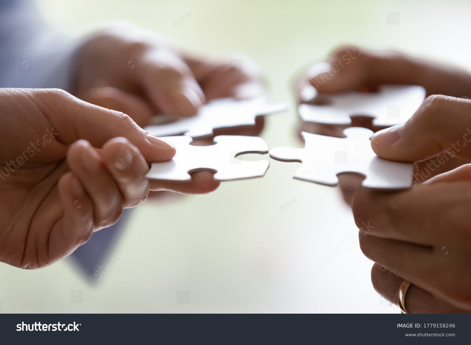 Close up hands of four businesspeople hold pieces of white puzzle, assemble jigsaw, put it together, joint path to problem solution, find way out exit of difficult situation. Support, teamwork concept #1779158246
