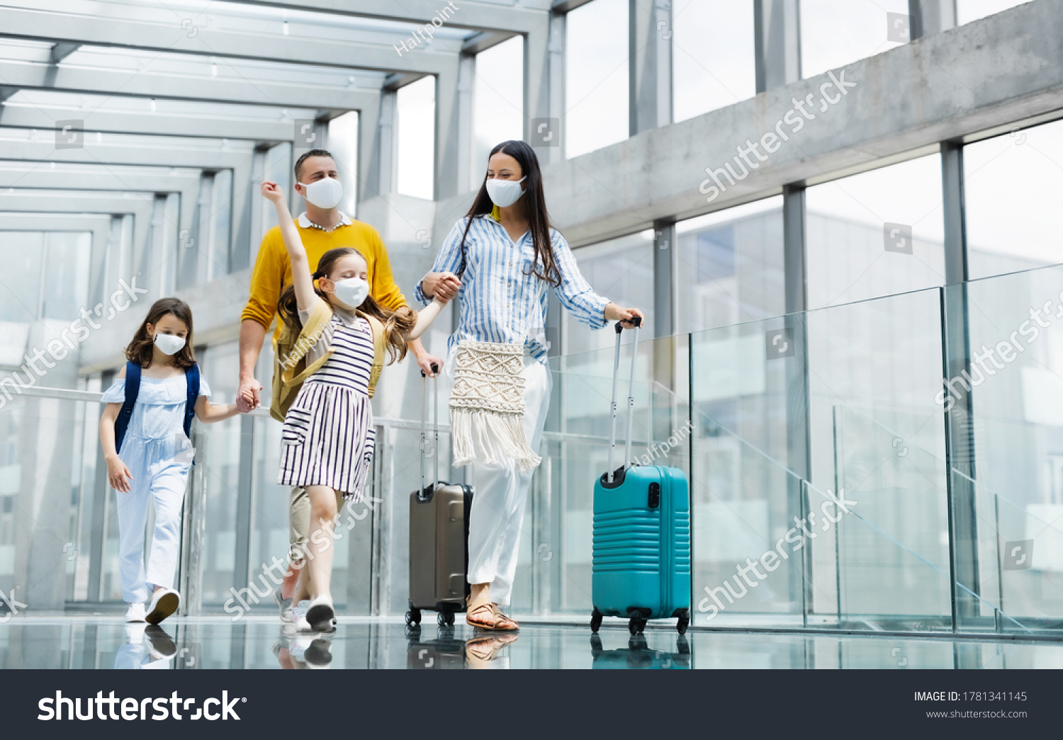 Family with two children going on holiday, wearing face masks at the airport. #1781341145