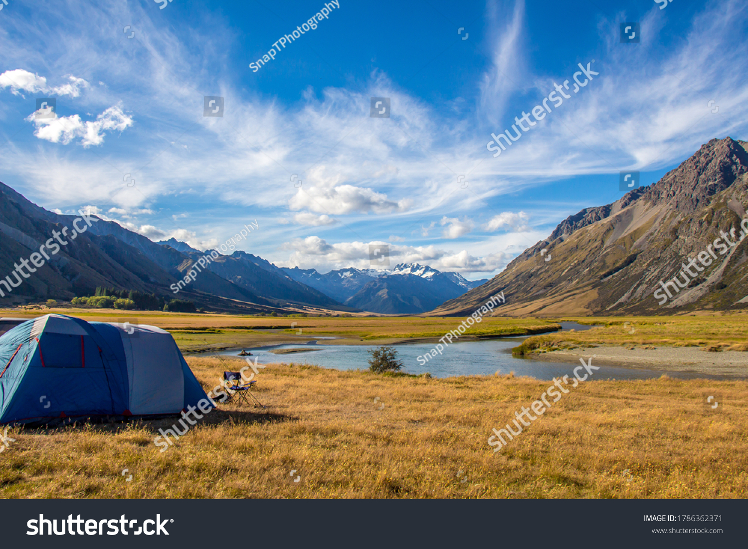 A tent pitched beside the Ahuriri River, surrounded by mountains, in Cantebury, South Island, New Zealand #1786362371