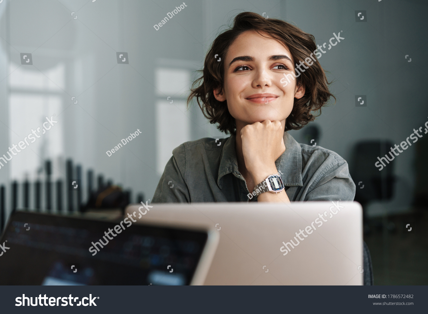 Image of young beautiful joyful woman smiling while working with laptop in office #1786572482