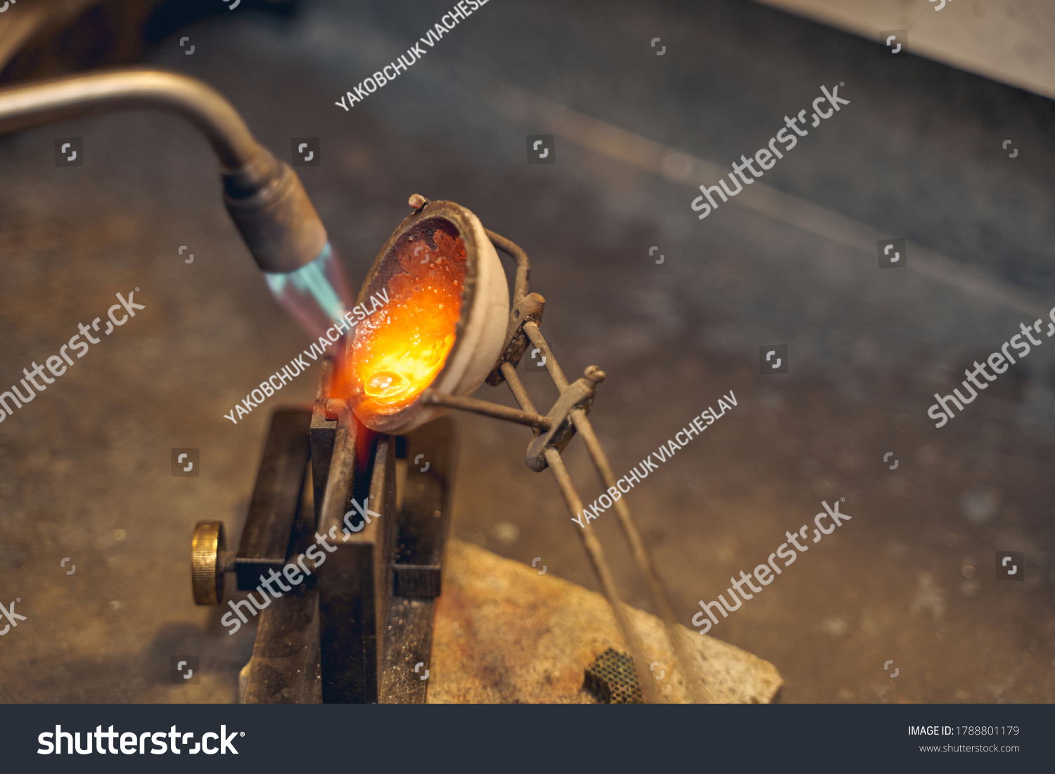 Smelted metal being poured by an experienced gold refiner from the crucible into a mold #1788801179