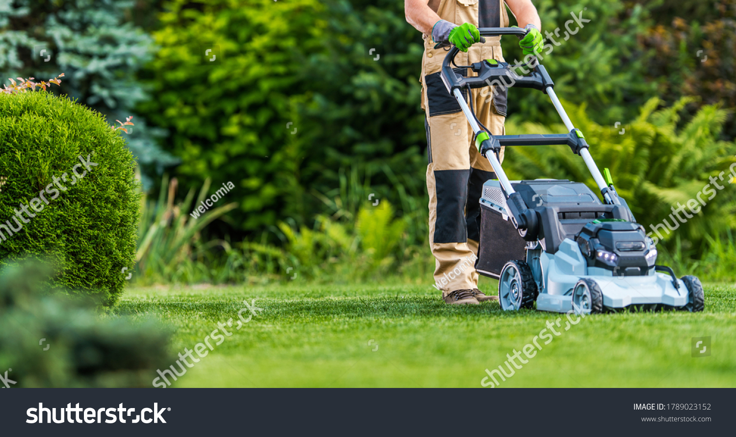 Professional Caucasian Gardener in His 40s Trimming Grass Lawn Using Modern Electric Cordless Mower. Landscaping Industry Theme. #1789023152