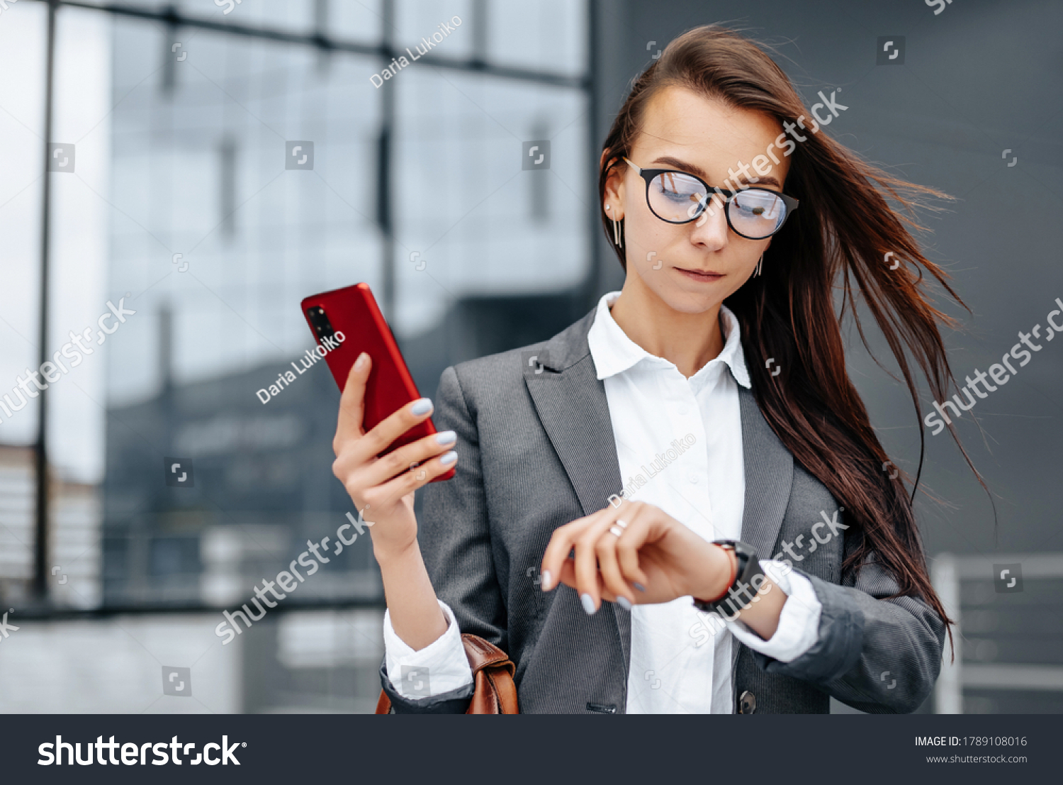 A business woman checks the time in the city during a working day waiting for a meeting. Discipline and timing. An employee goes towards a corporate meeting. #1789108016