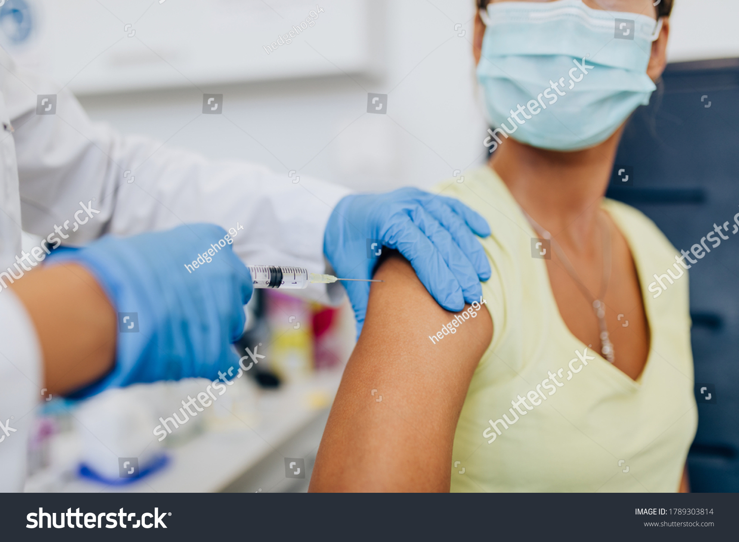 Female doctor or nurse giving shot or vaccine to a patient's shoulder. Vaccination and prevention against flu or virus pandemic.  #1789303814