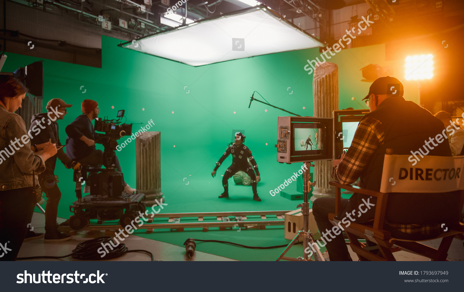 In the Big Film Studio Professional Crew Shooting Blockbuster Movie. Director Commands Cameraman to Start shooting Green Screen CGI Scene with Actor Wearing Motion Capture Suit and Head Rig #1793697949
