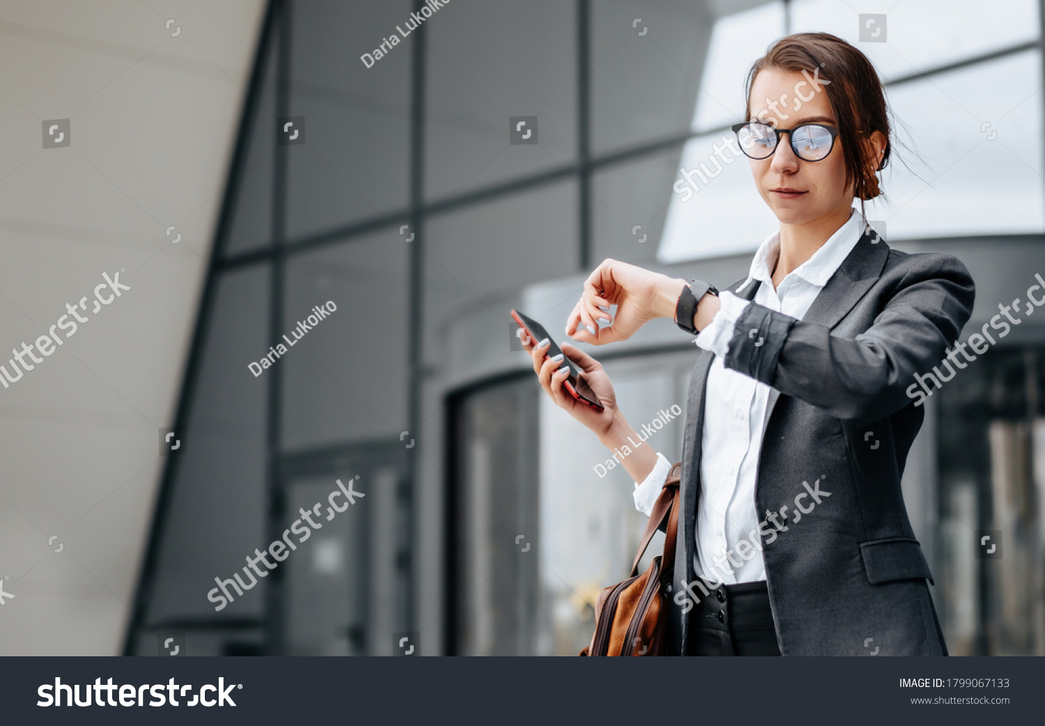 A business woman checks the time in the city during a working day waiting for a meeting. Discipline and timing. An employee goes towards a corporate meeting. #1799067133