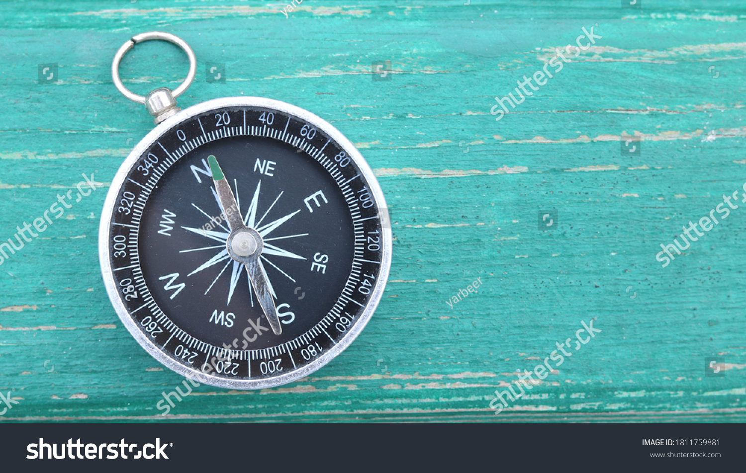 Classic round compass on green wooden vintage background as symbol of tourism with compass, travel with compass and outdoor activities with compass #1811759881