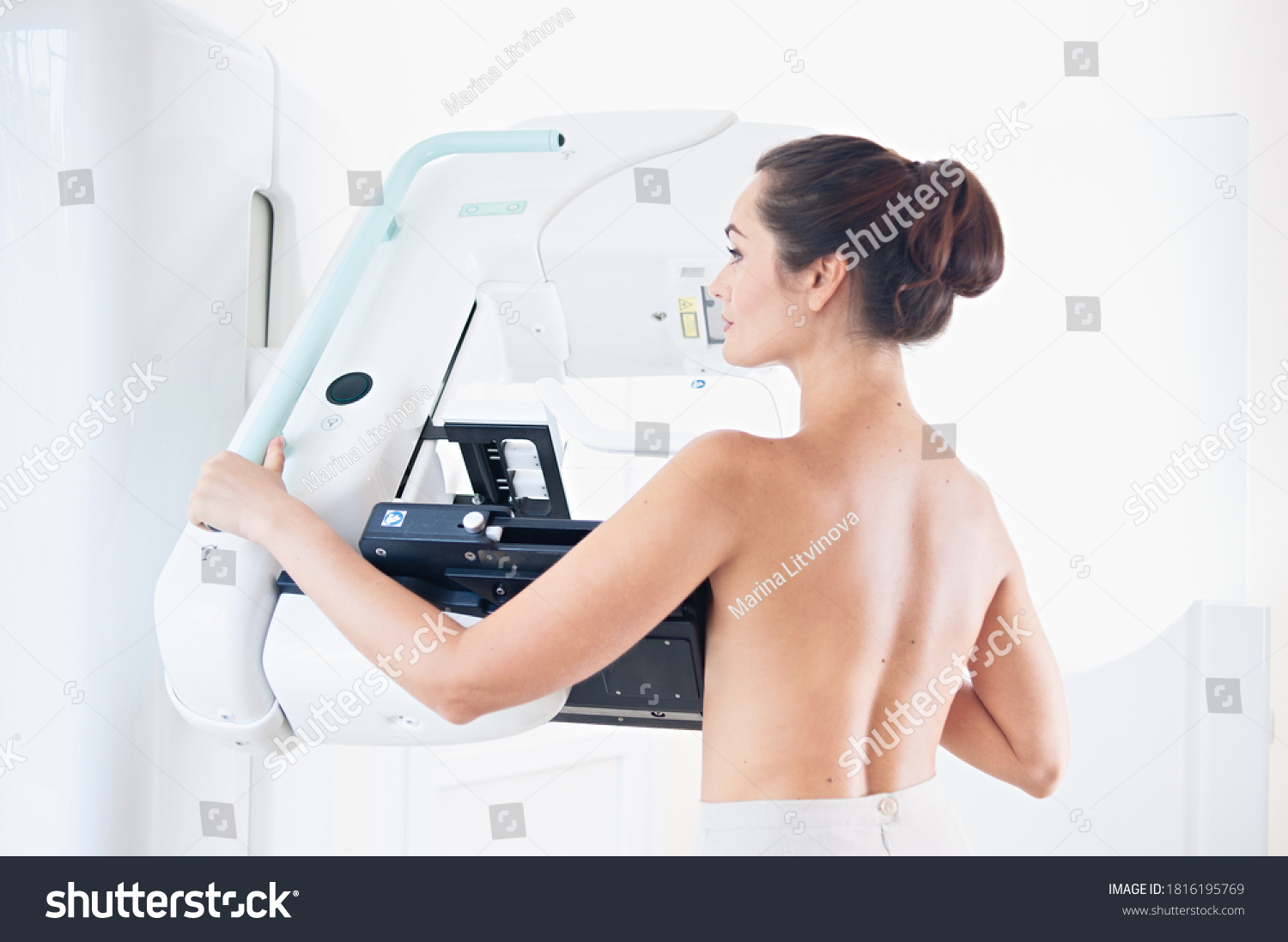 Young woman at breast cancer prevention screening at hospital. Hardware examination of the breast. Healthy young woman doing cancer prophylactic mammography scan. Modern hospital with hi-tech machine #1816195769