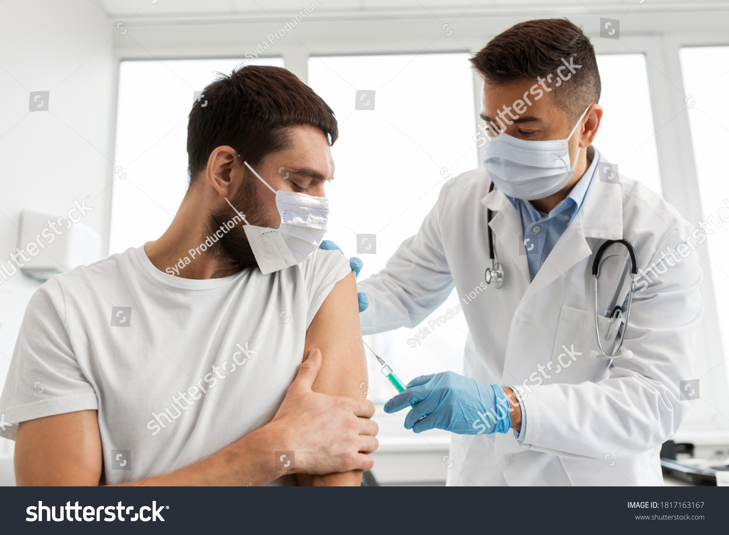 medicine, vaccination and healthcare concept - doctor wearing face protective medical mask for protection from virus disease with syringe doing injection of vaccine to male patient #1817163167