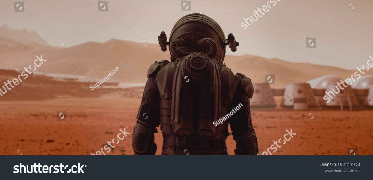 Back view of astronaut wearing space suit walking on a surface of a red planet. Martian base and rover in the background. Mars colonization concept #1817219624