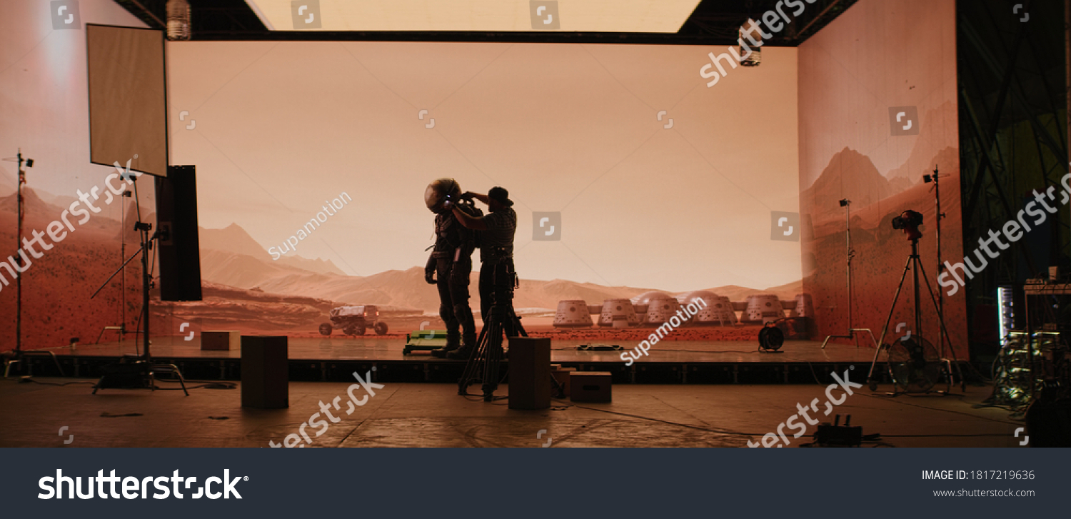Behind the scenes shot of virtual production stage with huge LED screens, cinematorgapher shooting Mars scene. Future of movie production #1817219636