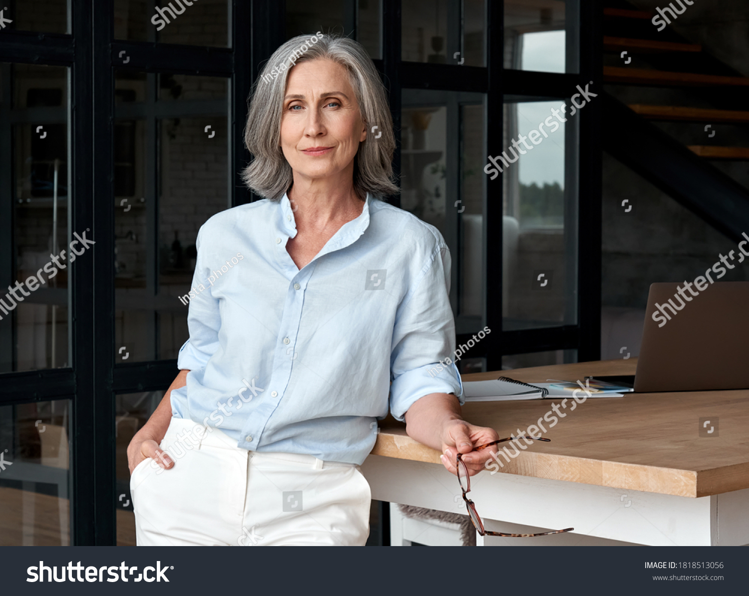 Confident stylish european mature middle aged woman standing at workplace. Stylish older senior businesswoman, 60s gray-haired lady executive leader manager looking at camera in office, portrait. #1818513056