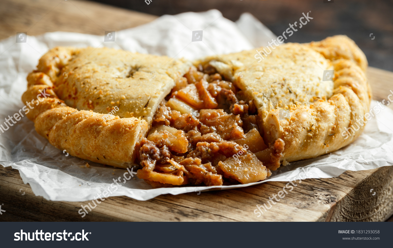 Traditional Cornish pasty filled with beef meat, potato and vegetables on black plate #1831293058