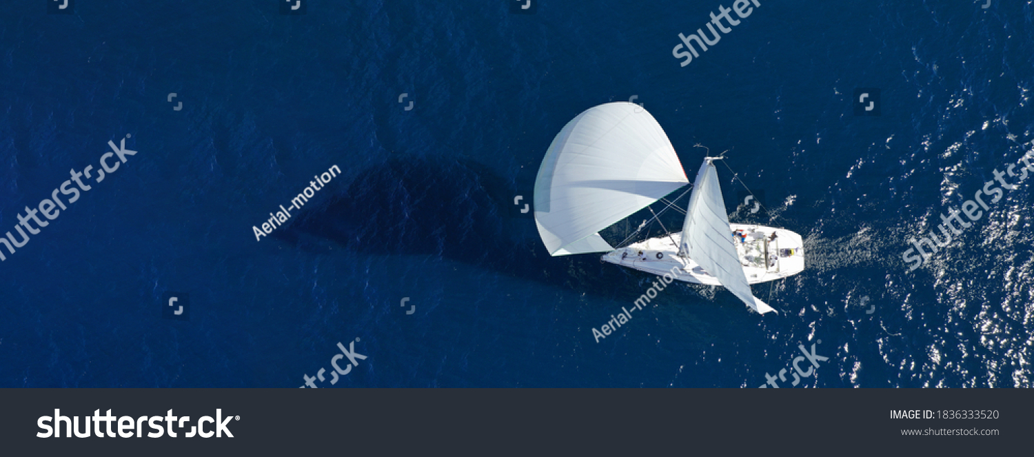 Aerial drone ultra wide panoramic photo with copy space of beautiful sail boat with white sails cruising deep blue sea near Mediterranean destination port #1836333520