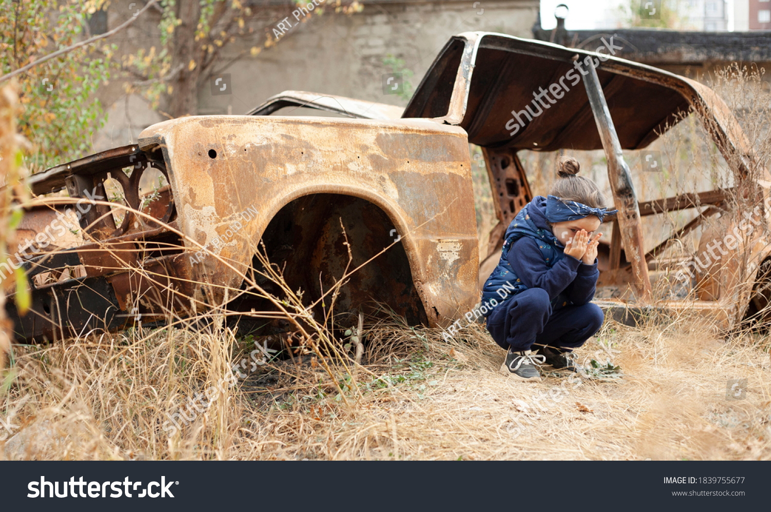 A little girl is crying near the burnt car. War in Donetsk. War Nagorno-Karabakh. Burned-out car. #1839755677