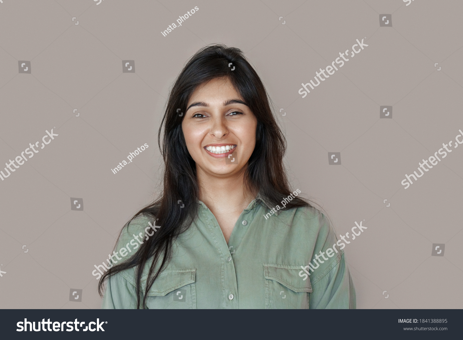 Smiling cheerful young adult indian woman looking at camera, happy pretty funny lady model laughing, feeling positive emotion standing isolated on brown background, face front headshot portrait. #1841388895