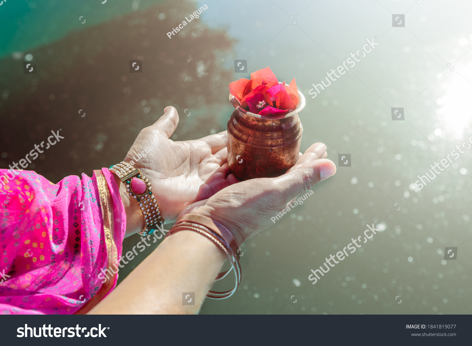 Hands of an Indian woman, pouring sacred water into the water of the Ganges. Doing a ritual (puja) in the river. #1841819077