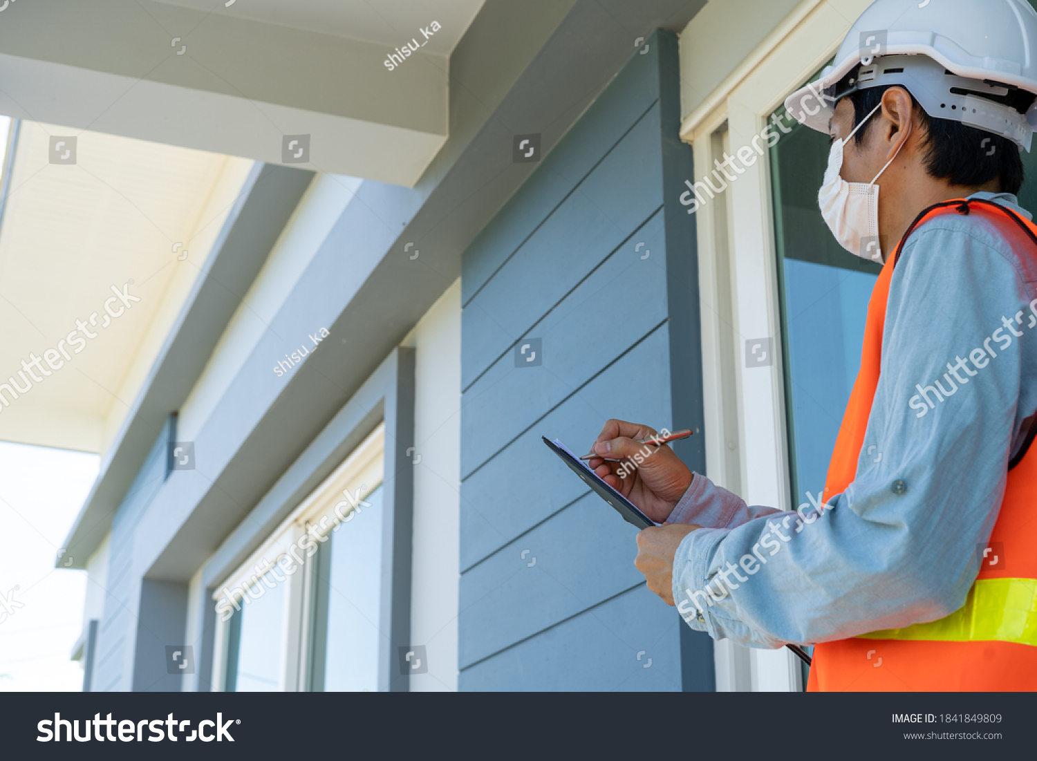 Engineers or inspectors in orange reflective vests are taking notes and checking with clipboards at the building's construction site, contractor inspections and engineering concepts. #1841849809