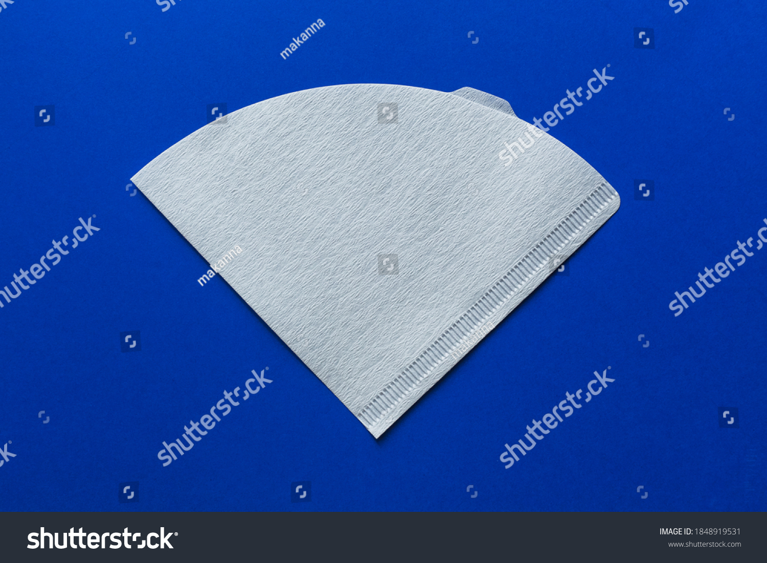 Bleached paper coffee filter isolated on a colored blue background. Alternative brewing pour over coffee. Minimalistic abstract background #1848919531