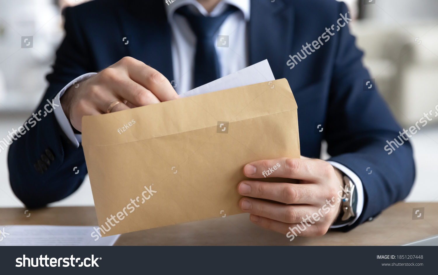 Close up young businessman entrepreneur in formal wear opening envelope with paperwork correspondence, male manager employee unpacking banking notification, law order or paper document at workplace. #1851207448