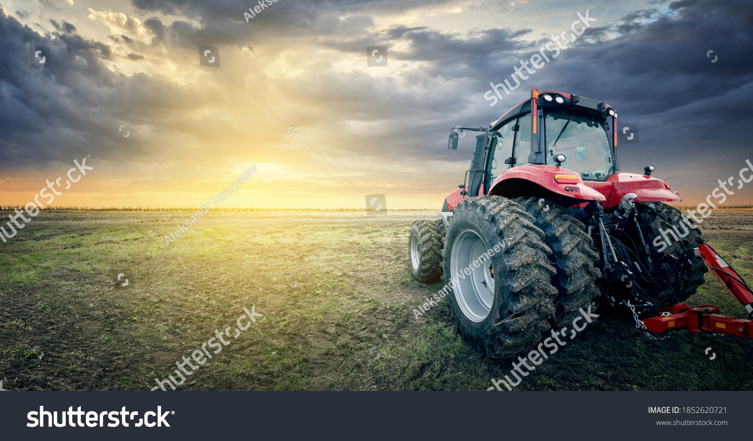 The tractor works in the field against the background of sunset. #1852620721