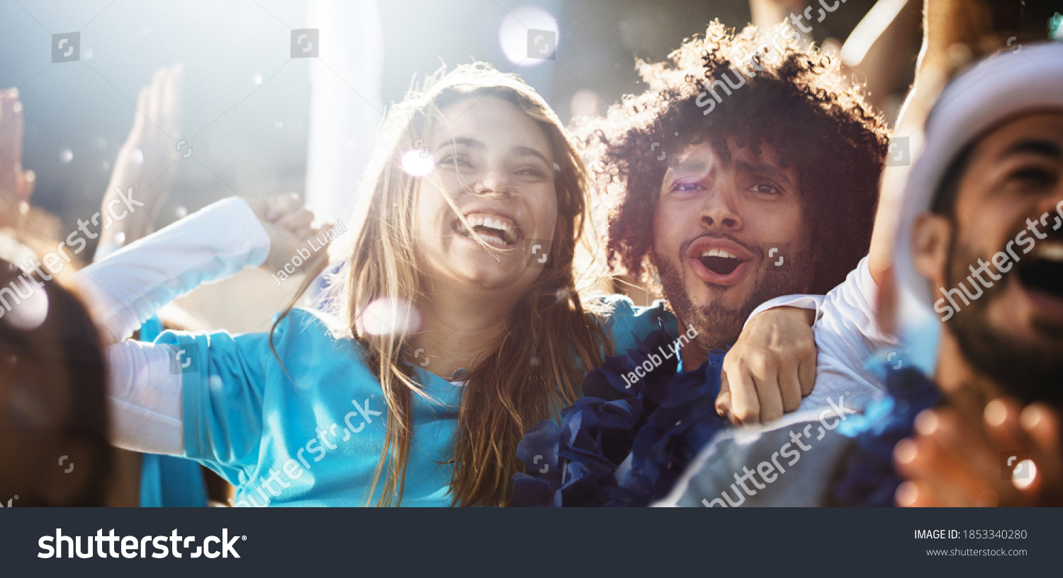 Cheerful couple cheering at a live soccer match. Group of people in the stadium cheering argentina football team. #1853340280