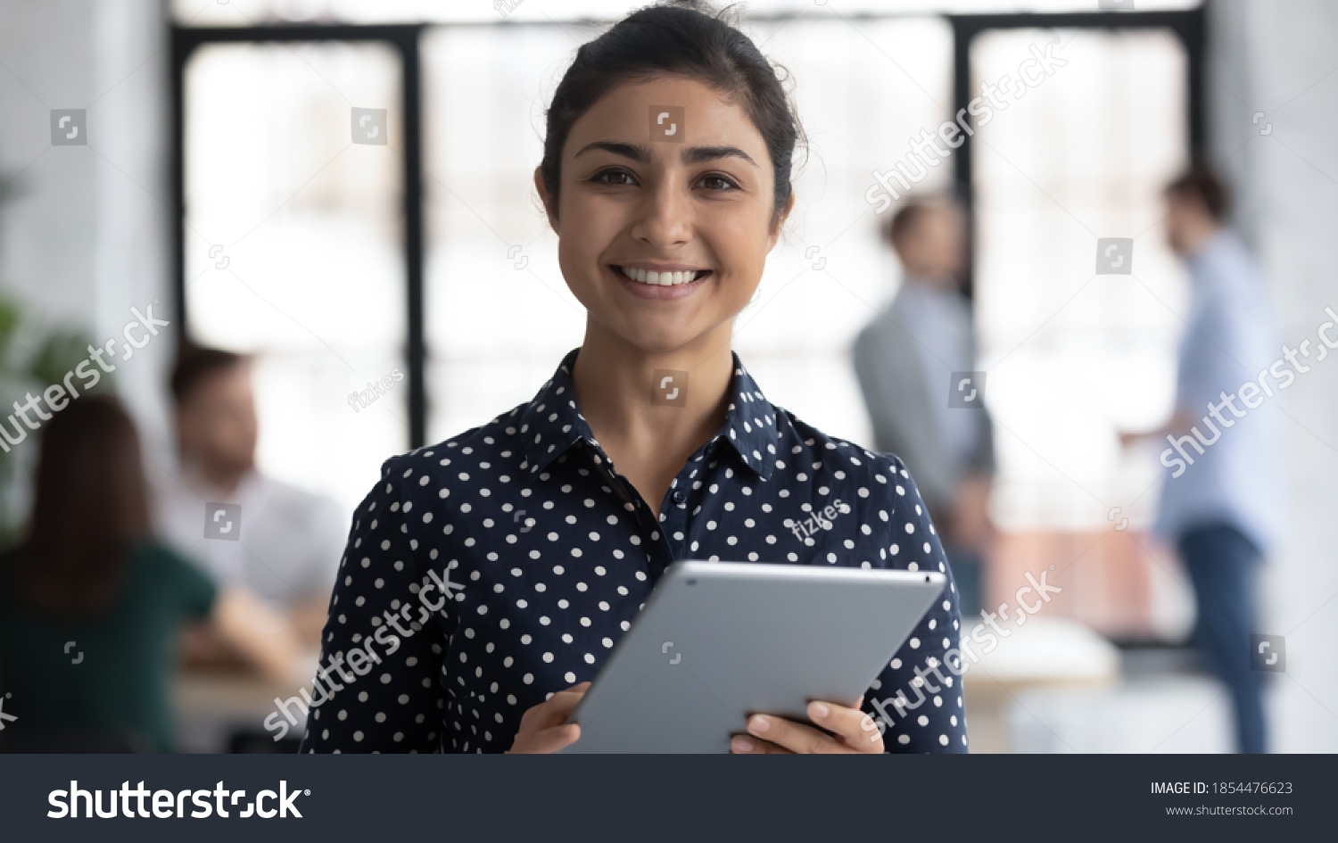 Glad to help you! Portrait of smiling confident indian female insurance broker bank manager hr assistant standing in open space office holding digital tablet looking at camera ready to assist client #1854476623