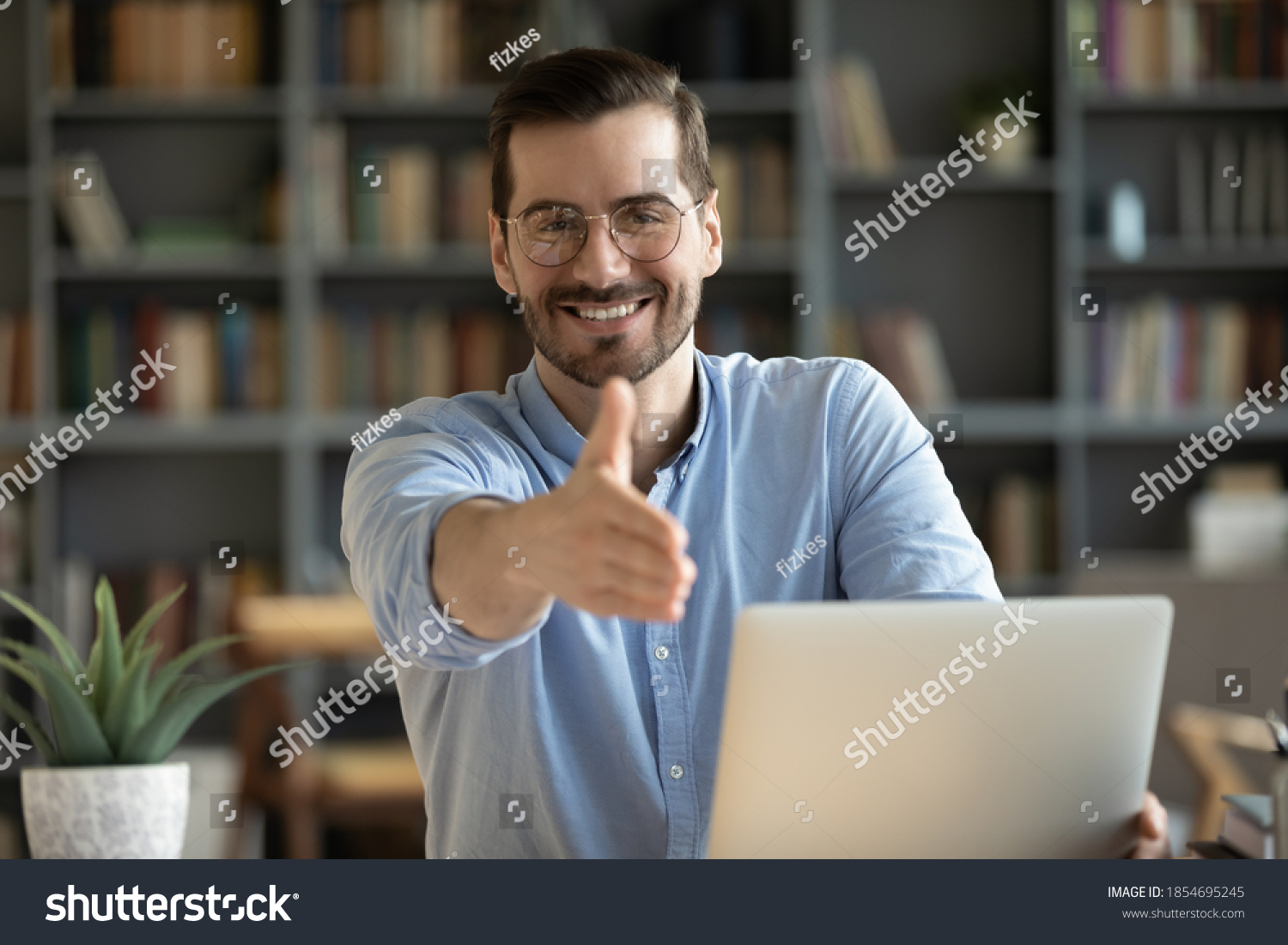 Human resource agent male recruiter sit at desk extends his hand to camera for handshake greeting applicant showing polite gesture start job interview in modern office. Welcoming, cooperation concept #1854695245