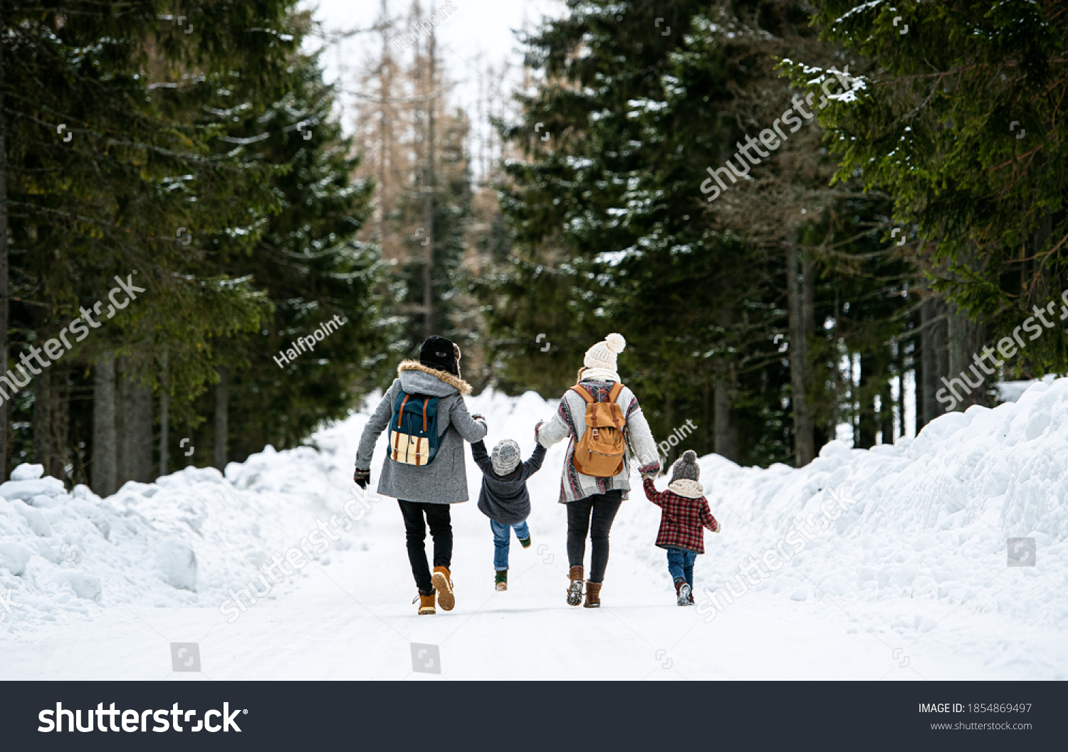 Rear view of family with two small children in winter nature, walking in the snow. #1854869497