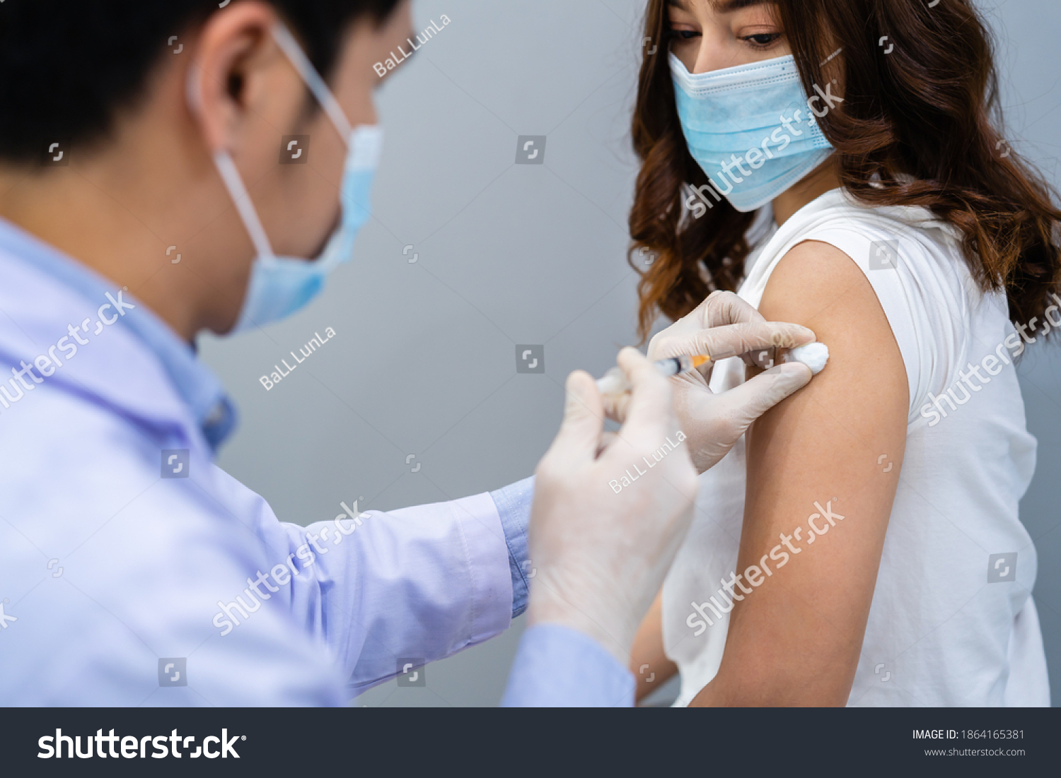doctor holding syringe and using cotton before make injection to patient in a medical mask. Covid-19 or coronavirus vaccine #1864165381