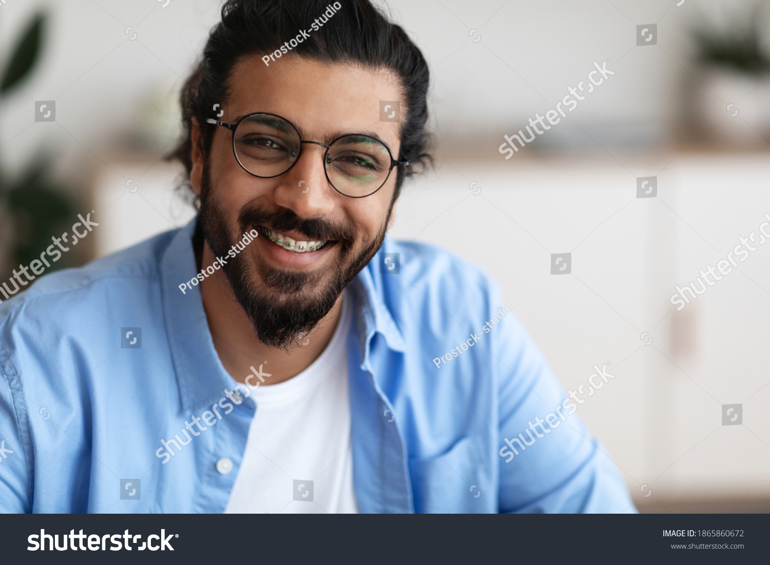 Closeup Portrait Of Positive Indian Guy With Dental Braces And Eyeglasses Smiling At Camera, Handsome Bearded Millennial Man With Brackets On Teeth Posing Indoors, Selective Focus With Copy Space #1865860672