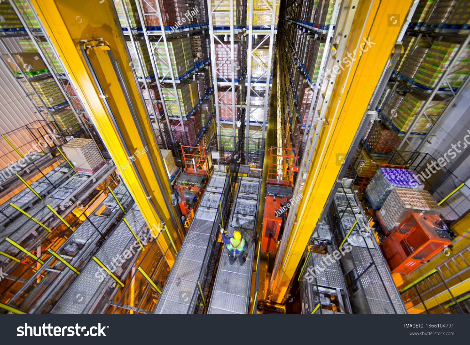 Wide shot of a worker standing below foodstuff merchandise stored in a warehouse with an automated storage and retrieval system  #1866104791